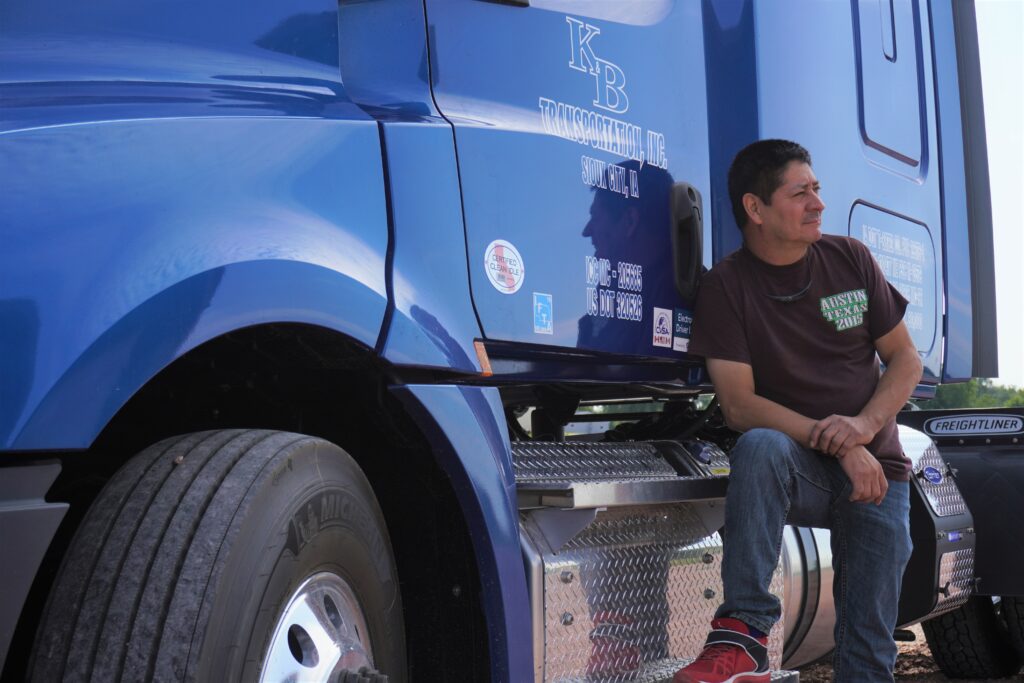 Driver sitting on step of truck looking away