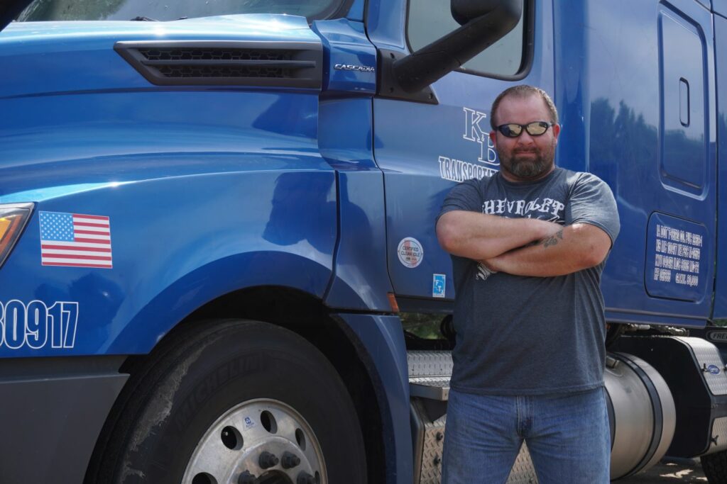 Driver standing next to truck with arms folded